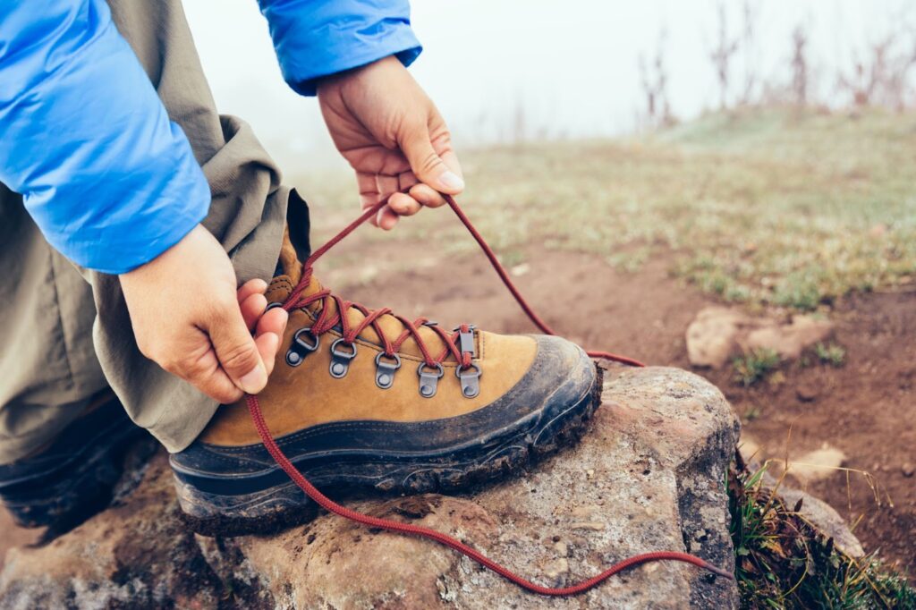 Prikaz muškarca koji veže cipele za planinarenje.