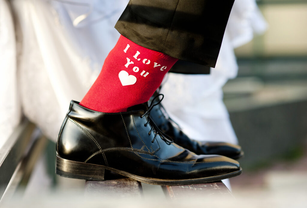 Prikaz muških lakiranih cipela za vjenčanje koje mladoženja nosi na crvene čarape s natpisom I love you.