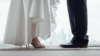 Mlada i mladoženja u odjeći za vjenčanje. Mladenka nosi svečane cipele za vjenčanje s otvorenim prstima, ukrašene cirkonima, a mladoženja nosi svečane cipele za vjenčanje u crnoj boji.