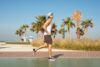 Mladić trči u muškoj sportskoj obući, palme i plaža u pozadini